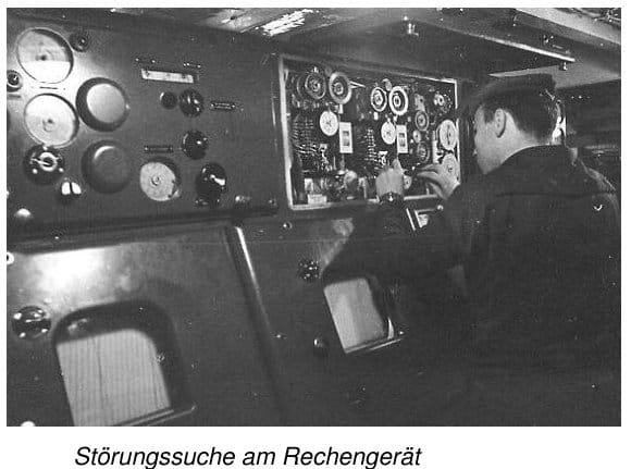 Ein Marineangehöriger arbeitet in einem engen Bordraum an einem geöffneten Schaltschrank des artilleristischen Rechengerätes, daneben eine Bedientafel mit großen Rundinstrumenten